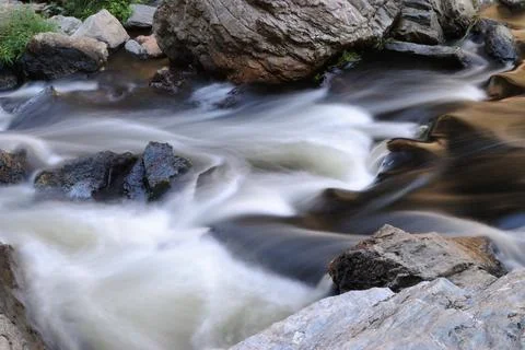 Water from a river flowing between rocks at great speed, milk effect Stock Photos