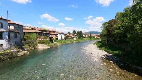 The water of a river flows fast between the houses under a blue sky Stock Footage 154912237