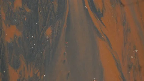 Water from a river flows over black and orange volcanic sand, in Vietnam Stock Footage 232393520