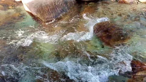 Water from a river gracefully flowing over rocks Stock Footage 278053714