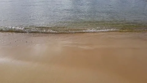 Water rolling into a beach waves with slow pan up to see the distant shore 库存影片 83183533