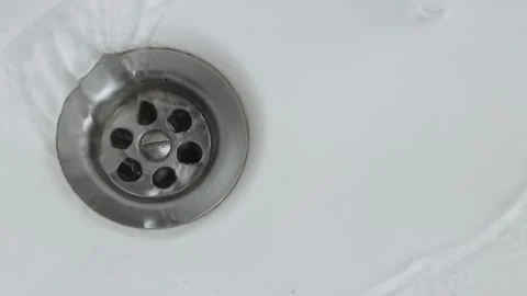 Water running and flowing down the drain. Swirling through metallic sewer sink Stock Footage 318851106