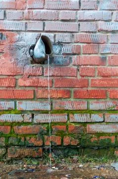 Water running down an old battered water pipe Foto stock