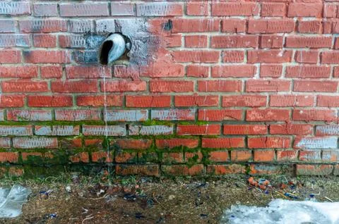 Water running down an old battered water pipe Stock Photos