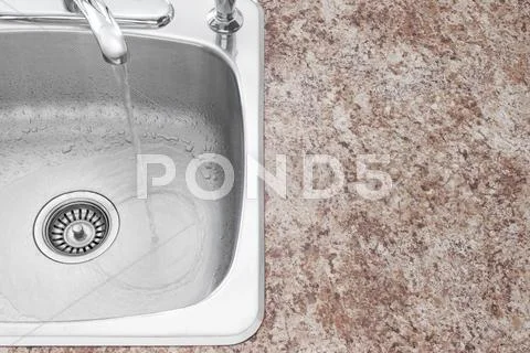 Water running from kitchen faucet and countertop detail Stock Photos