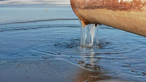 Water running out of drain pipe into frozen lake, Finland Stock Footage 171664398