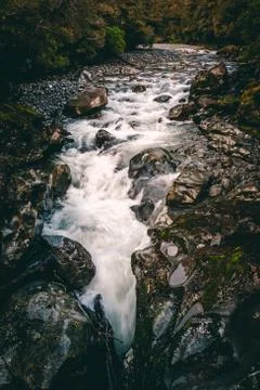 Water running through stream over dark rocks from water fall Stock Photos