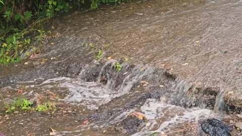 Water rushes over a surface after a heavy rain. The clip captures the splashing Видео 344668099