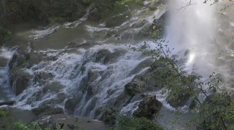 Water Rushing through Rocks at the Bottom of a Waterfall with Tree Branches Stock Footage 68995944