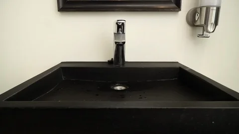 Water saving concept. Water flows from a chrome steel bathroom tap. Close up Stockbeeldmateriaal 109096328