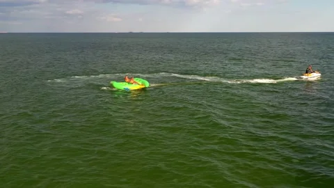 A water scooter pulls people on an inflatable mattress across the sea. Stock Footage 137234217