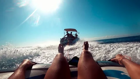 Water skiing over inflatable donut pulled by motorboat. Aquatic sports, Vidéo 230869322