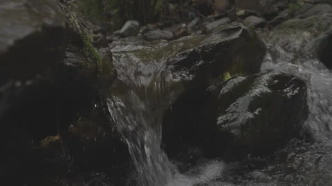 Water in small mountain river flows through stone barrier and falls down Stock Footage 260545377