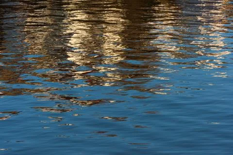 Water with small waves. Reflections of blue sky and buildings. Stock Photos