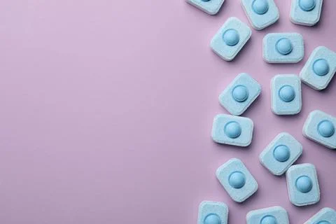 Water softener tablets on violet background, flat lay. Space for text Stockfoto's
