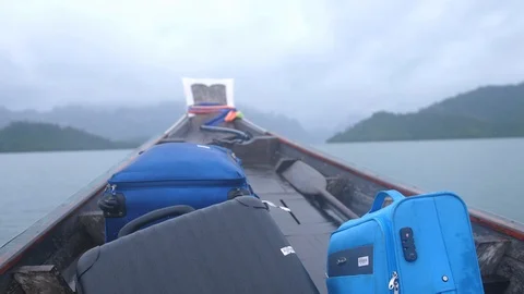 Water splash along side the fast moving tourist wooden boat with a suitcase in Stock Footage 105638969
