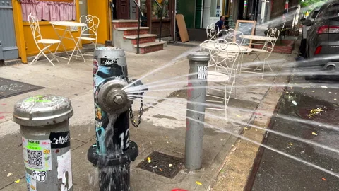 Water splash from Fire Hydrant in front of Cafe at East Village in NYC Stock Footage 281017979