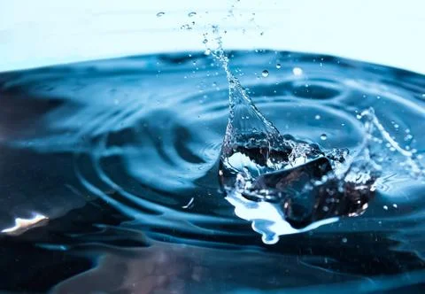 Water splash. Ice cubes falling into the blue water. Splash of ice water. Wat Stock Photos