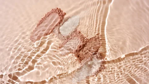Water splash over beige powder for creative ad Stock Footage 337765657