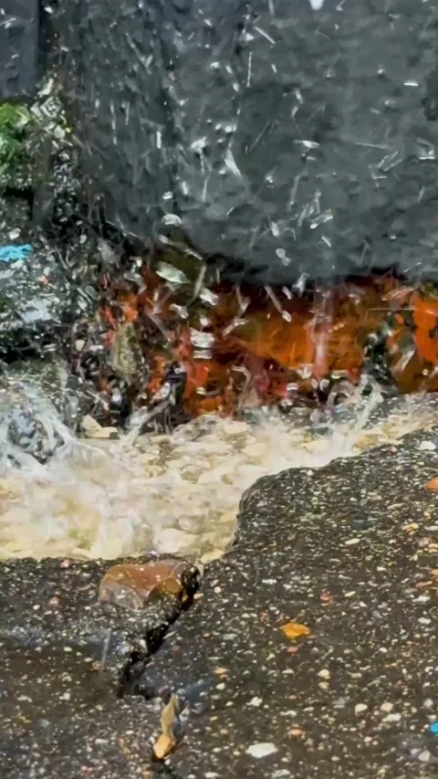 Water splash from rain impact hitting cracked asphalt street puddle in macro Stock Footage 330122604