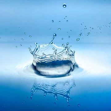 Water splash with reflection and drops on a blue background Stock Photos