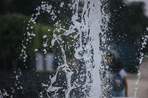 Water splashes create a dynamic pattern on a glass surface with blurred fig.. Stock Photos