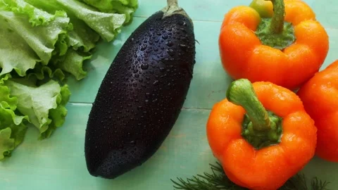 Water splashes fall on three sweet orange peppers and an eggplant Stock Footage 237307092