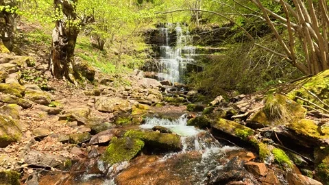 Water splashes gently onto smooth, earthy rocks. Tupavica Waterfall Vídeos de archivo 335533807