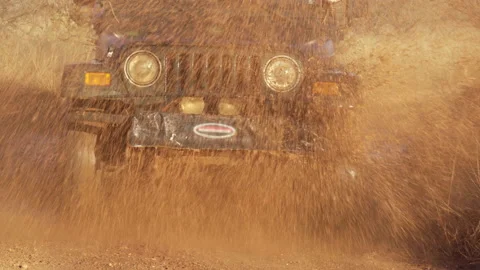 Water splashes from a puddle as a 4WD car, 4x4, drives through Stock Footage 212610794