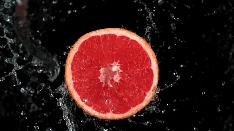 Water splashes on red grapefruit in slow motion against black background Stock Footage 327573109