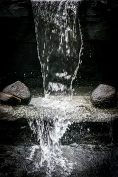 Water splashing between two rocks under a waterfall Stock Photos