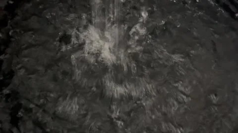 Water Splashing into a Dark Pool Creating Ripples and Bubbles Stock Footage 340988997