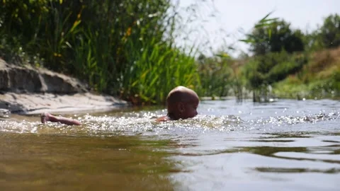 Water splashing scene captures dynamic motion of a child diving into a river Video stock 324753631