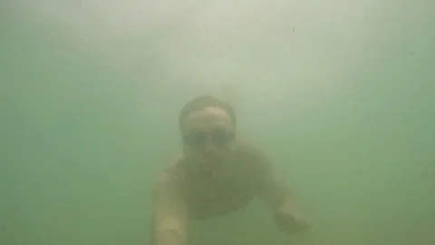 Water sports. Swimmer diver male dives into the sea, swimming in muddy water Stock Footage