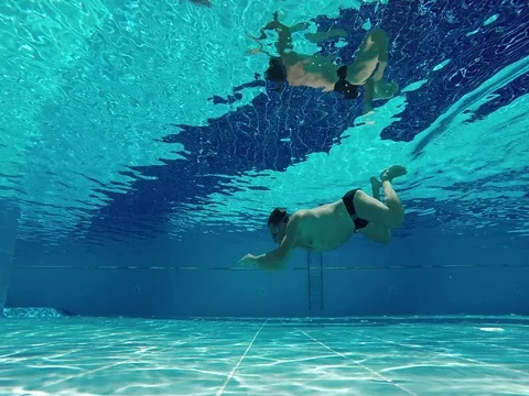 Water sports. Swimmer diver male dives in pool, swimming in clear sunny water Stock Footage