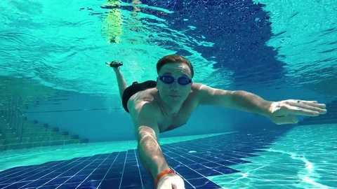 Water sports. Swimmer man dives in the sunny pool, swimming in clear water Stock Footage