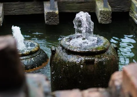 Water Spouting from Old Clay Pot Inside Pool of Water Stock Photos
