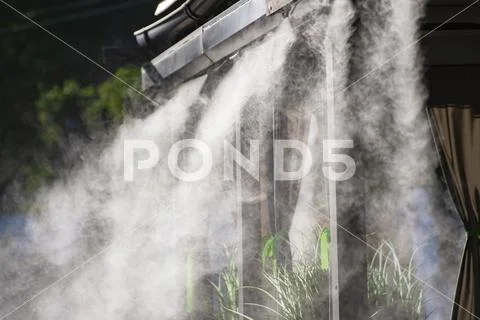 Water spray system for cooling in a public cafe at the boiling hot summer day Stock Photos