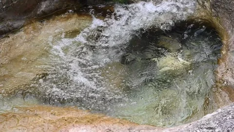 Water squirling in a pool of a mountain stream in slow motion Video stock 260864050