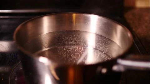 Water starting to boil time lapse in silver pan close up and stream Stock Footage 150990800