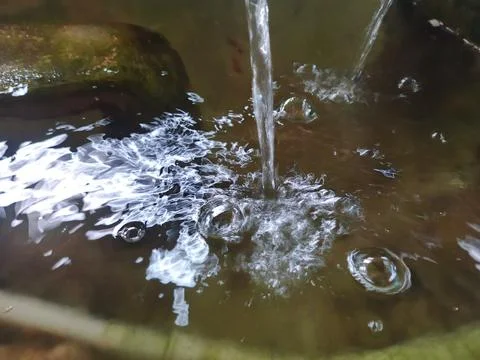 Water Stream Falling into a Pond Creating Bubbles and Ripples on the Surface Stock Photos