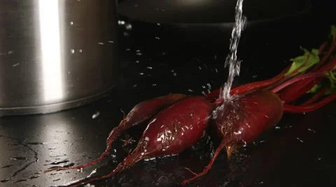 Water stream falls on a beets on a black table Stockbeeldmateriaal 68155755
