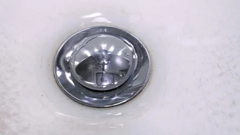 Water stream flowing down into white sink drain Vidéo 302540877