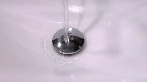 Water stream flowing down into white sink drain Stock Footage 302542161