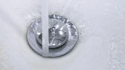 Water stream flowing down into white sink drain Stock-Footage 302542246