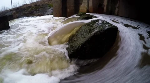 Water stream flowing out the underground tunnel into the river Stock Footage 47487898