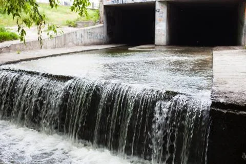 Water stream flowing out the underground tunnel Stock Photos