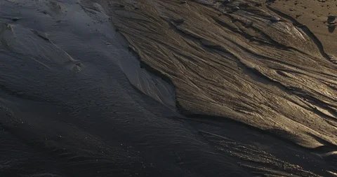 Water stream flowing over the wet sand on beach Video stock 103807583
