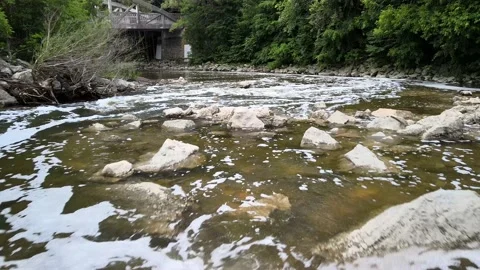 Water stream flowing through rocks and beneath old bridge beautiful summer day Stockbeeldmateriaal 133643401
