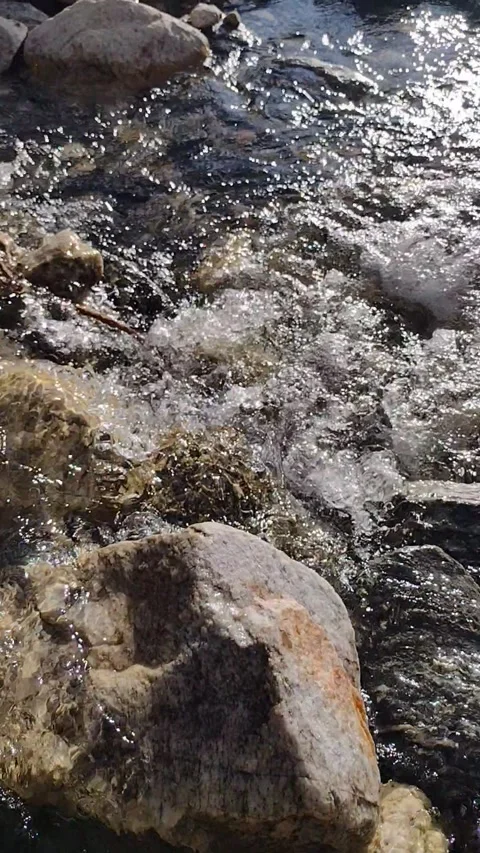 Water from a stream going down between rocks in a sunny day Stock Footage 267707510